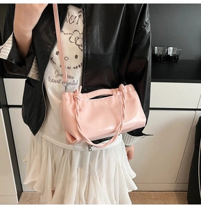 Detail of pink glossy leather handbag showing drawstring texture and knotted handle