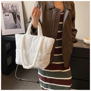 Vue détaillée d'un sac fourre-tout matelassé blanc porté avec une veste en cuir