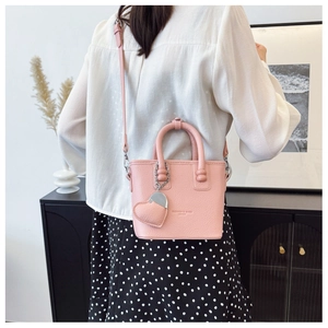 Detail der rosa Leder-Eimertasche mit Herzanhänger an einem Model getragen