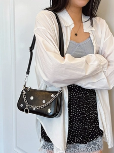 Borsa a mezzaluna nera minimalista con catene argento indossata da modella alla moda