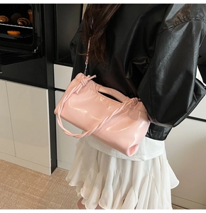 Detail of pink patent leather handbag with knot drawstring detail in home setting