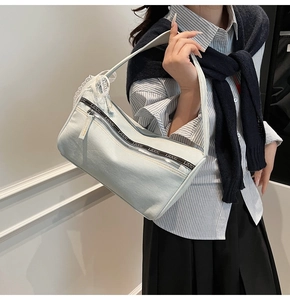 Detail of light blue denim baguette bag featuring white lace trim and LIUU logo webbing