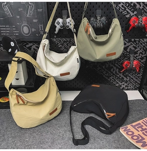 Detailed display of four nylon hobo bags in beige, white, green and black with wide straps