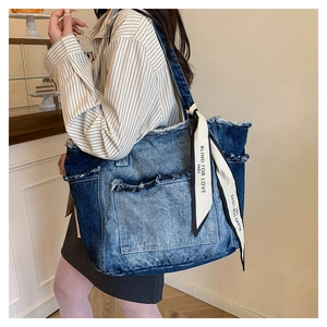 Détail du sac cabas en denim avec bords effilochés et foulard décoratif en soie à logo