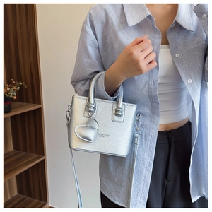 Details der silbernen Handtasche mit Herzanhänger und abnehmbarem Schultergurt