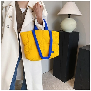 Détail du sac cabas matelassé jaune avec poignée contrastée bleue et texture rembourrée