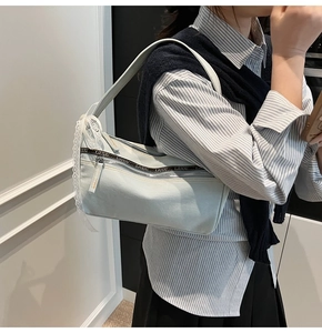 Detail of light blue denim baguette bag with white lace ribbon and branded webbing strap