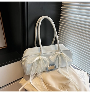 Detail der hellblauen Denim Boston Bag mit weißen Spitzenschleifen und Fransen-Anhänger