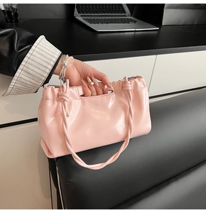 Detail of light pink glossy patent leather handbag with drawstring pleated cloud design