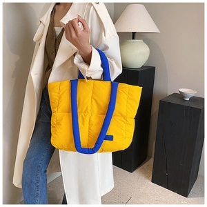Détail du sac matelassé jaune avec anses cylindriques bleues et coutures contrastées