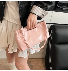 Close-up of light pink glossy PU leather handbag with drawstring detail and knotted handle