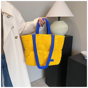 Détail du sac fourre-tout matelassé en nylon avec poignées bleues et design jaune