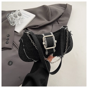 Close-up of black denim shoulder bag with frayed edges and oversized silver buckle detail