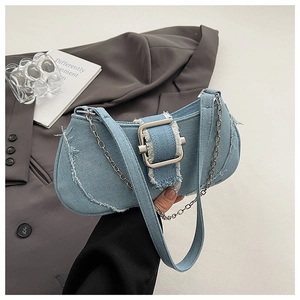 Macro detail of denim underarm bag featuring frayed edges and a metallic buckle closure