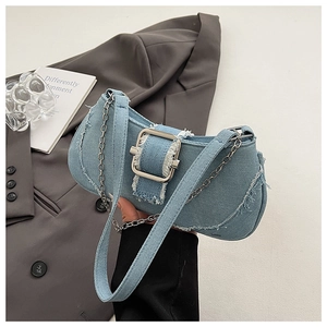 Detailed shot of light blue denim shoulder bag with frayed edges and silver buckle