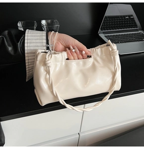Detailed view of cream PU shoulder bag with braided handle in a minimalist office setting