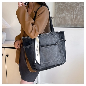 Détail d'un sac cabas en denim avec bords effilochés et foulard en soie au manche