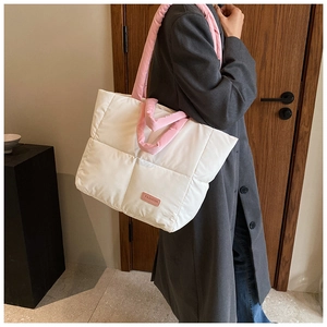 Détail de l'étiquette rose et texture matelassée sur le sac fourre-tout blanc