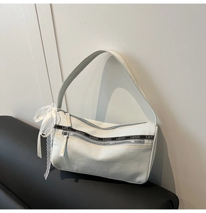 Detail showing white denim baguette bag texture with silver zippers and lace bow