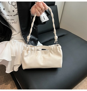 Detail of cream white PU leather bag with pleated design and twisted rope handle