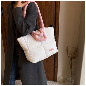 Détail du sac cabas matelassé blanc avec anses roses et étiquette de mode