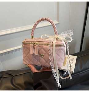 Pink quilted mini box bag with woven handle and lace bow detail in hand