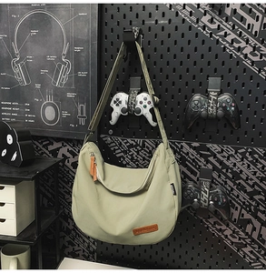 Detail of light green nylon crescent bag with leather zipper pull and side label