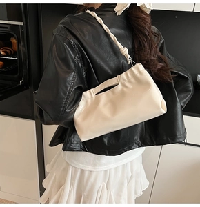 Detail of cream drawstring tote bag with pleated design and braided handle in fashion style