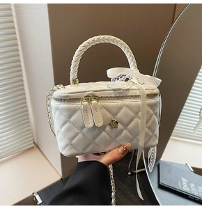 Detail of white quilted box bag with camellia metal hardware and chain strap
