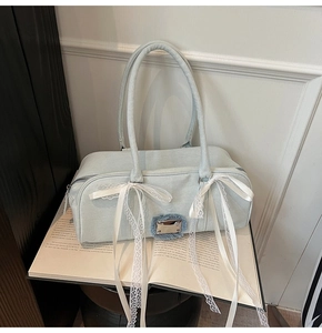 Detailaufnahme der hellblauen Segeltuchtasche mit weißen Spitzenschleifen und Metallschnalle