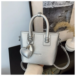 Detail der silbernen Mini-Tasche mit Herzanhänger und modischer Gravur im Fokus