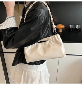 Detail of glossy cream PU leather drawstring bag with braided rope shoulder strap