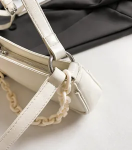Close-up of white underarm bag with silver hardware and thick resin chain detail