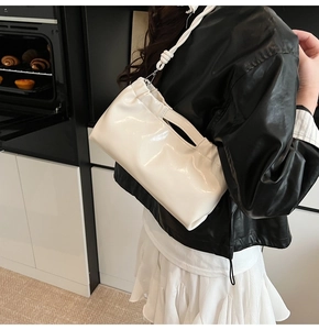 Close-up of white glossy PU leather handbag with drawstring detail and silver hardware