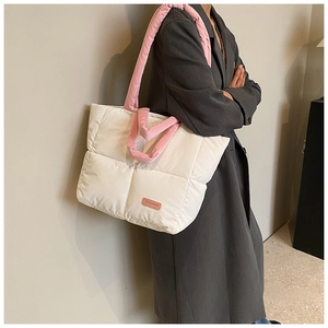 Vue latérale du sac fourre-tout matelassé blanc avec anses roses sur un manteau gris
