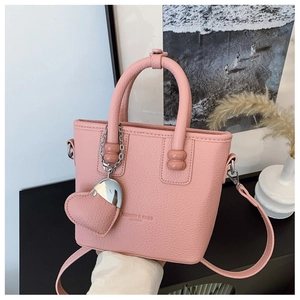 Nahaufnahme der rosa Leder-Eimertasche mit Herzanhänger in wohnlicher Kulisse