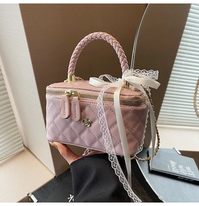 Detail of pink quilted leather bag with lace bow, golden flower, and braided handle
