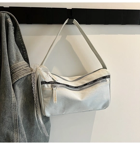 Detail of light blue denim baguette bag with lace ribbon and zipper webbing details