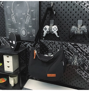 Detail of black nylon dumpling bag with orange leather logo on a tech style background