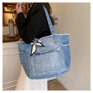 Détail du sac cabas en jean avec bords effilochés et nœud décoratif sur la poignée