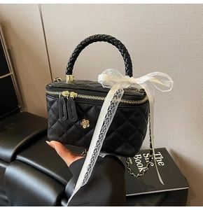 Detail of black quilted vanity bag with golden flower clasp and lace ribbon decoration