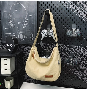 Macro detail of beige nylon dumpling bag showing premium texture and brown leather logo patch