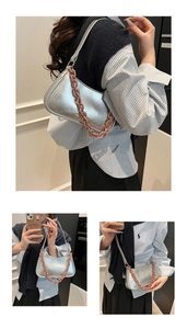 Detail of silver metallic underarm bag featuring a chunky brown decorative chain strap