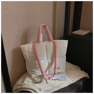 Détail macro du sac cabas matelassé beige avec poignées contrastées roses rembourrées