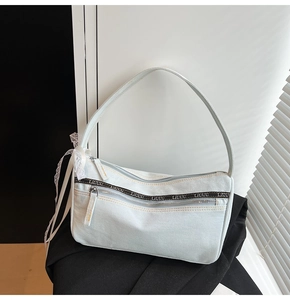 Detail of light blue denim baguette bag featuring lace accents and branded webbing strap