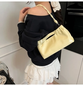Detail of light yellow ruched PU leather bag with handle and slim shoulder strap