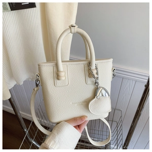 Detail der cremeweißen Beuteltasche mit Kiesellederstruktur und Herzanhänger