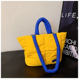 Détail du sac fourre-tout matelassé jaune avec anses bleues contrastées et étiquette mode