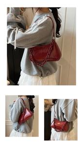 Close-up of wine red underarm bag featuring glossy wrinkled leather and thick chain strap