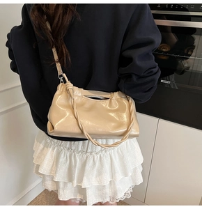 Close-up of beige glossy PU leather bag featuring unique woven handle and pleated design